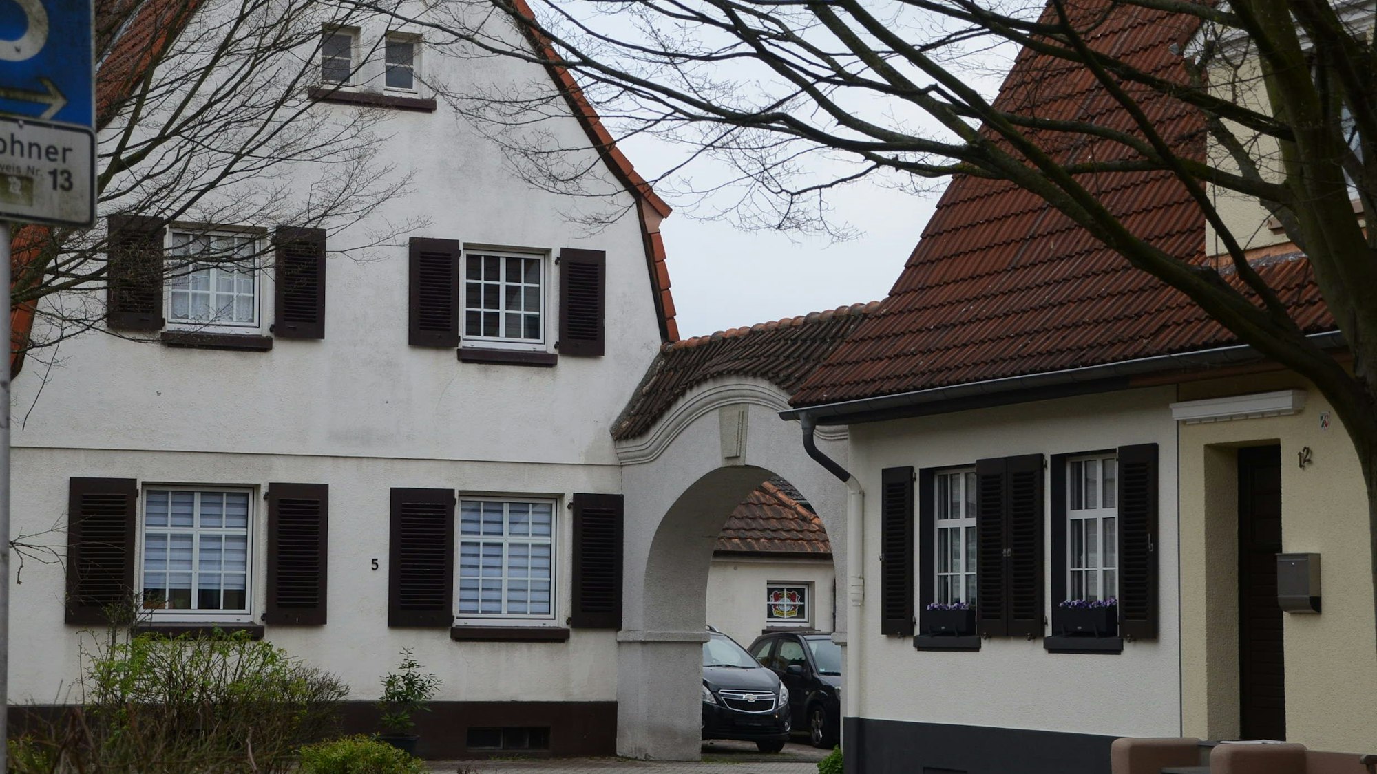 Häuser einer Arbeitersiedlung; die Häuser haben Sprossenfenster und dunkelbraune Fensterläden.