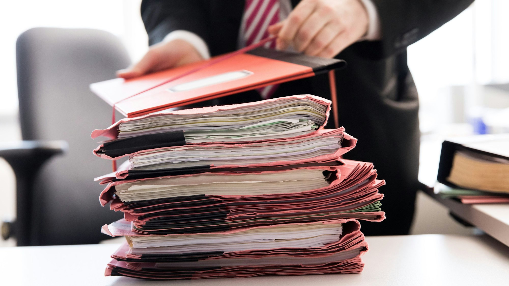 Ein Oberstaatsanwalt bindet einen Stapel Gerichtsakten zusammen.