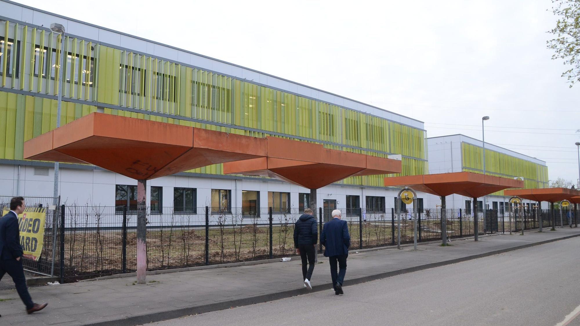 Fußgänger gehen auf einem Bürgersteig neben der Gertrud-Koch-Gesamtschule.