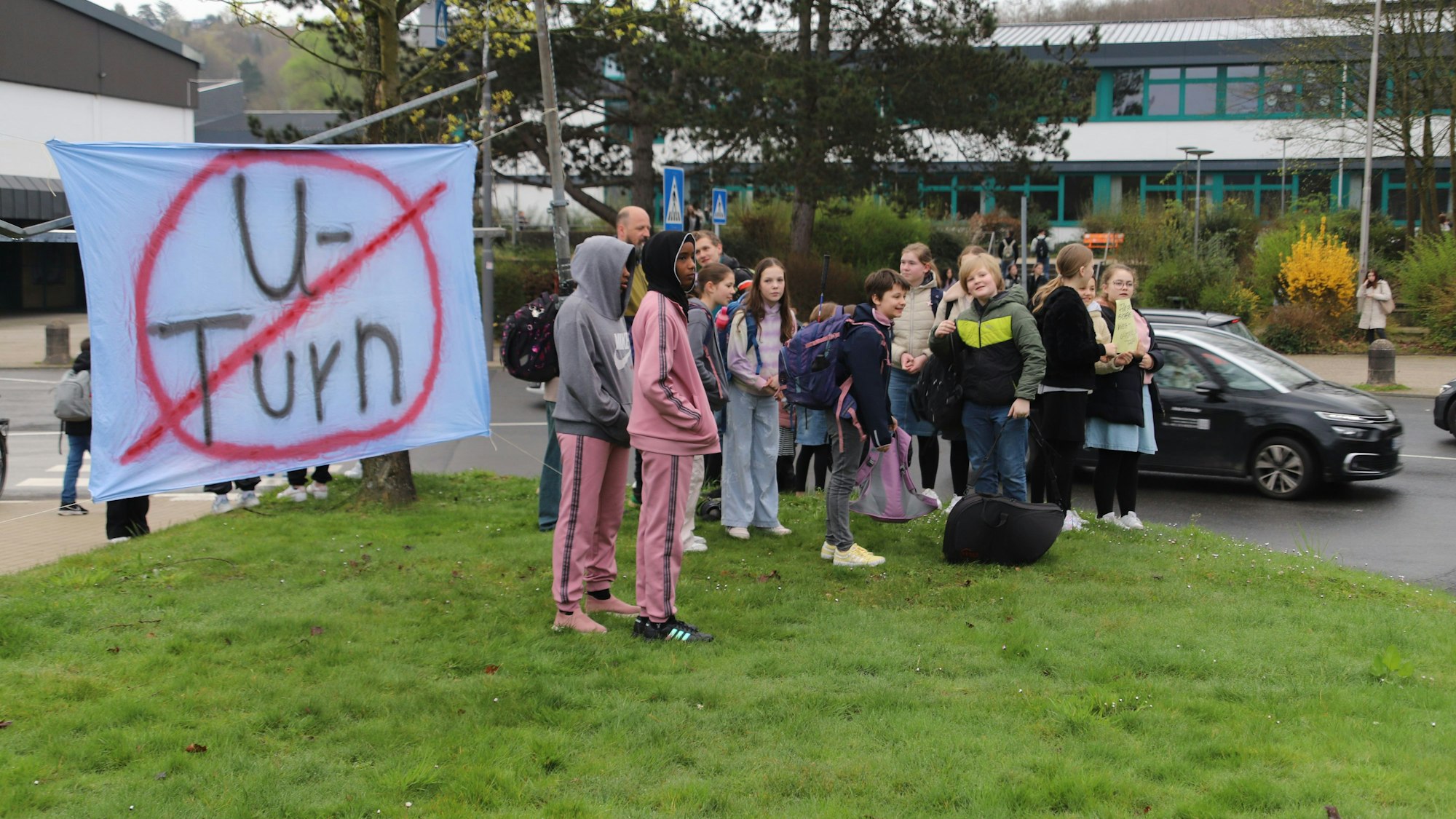 Auf einem Transparent mit der rot durchgestrichenen Aufschrift U-Turn stehen zahlreiche Schülerinnen und Schüler. Sie kamen zu der Demonstration für einen sicheren Schulweg und gegen U-Turns. Drei Menschen waren angemeldet, es kamen rund 40.