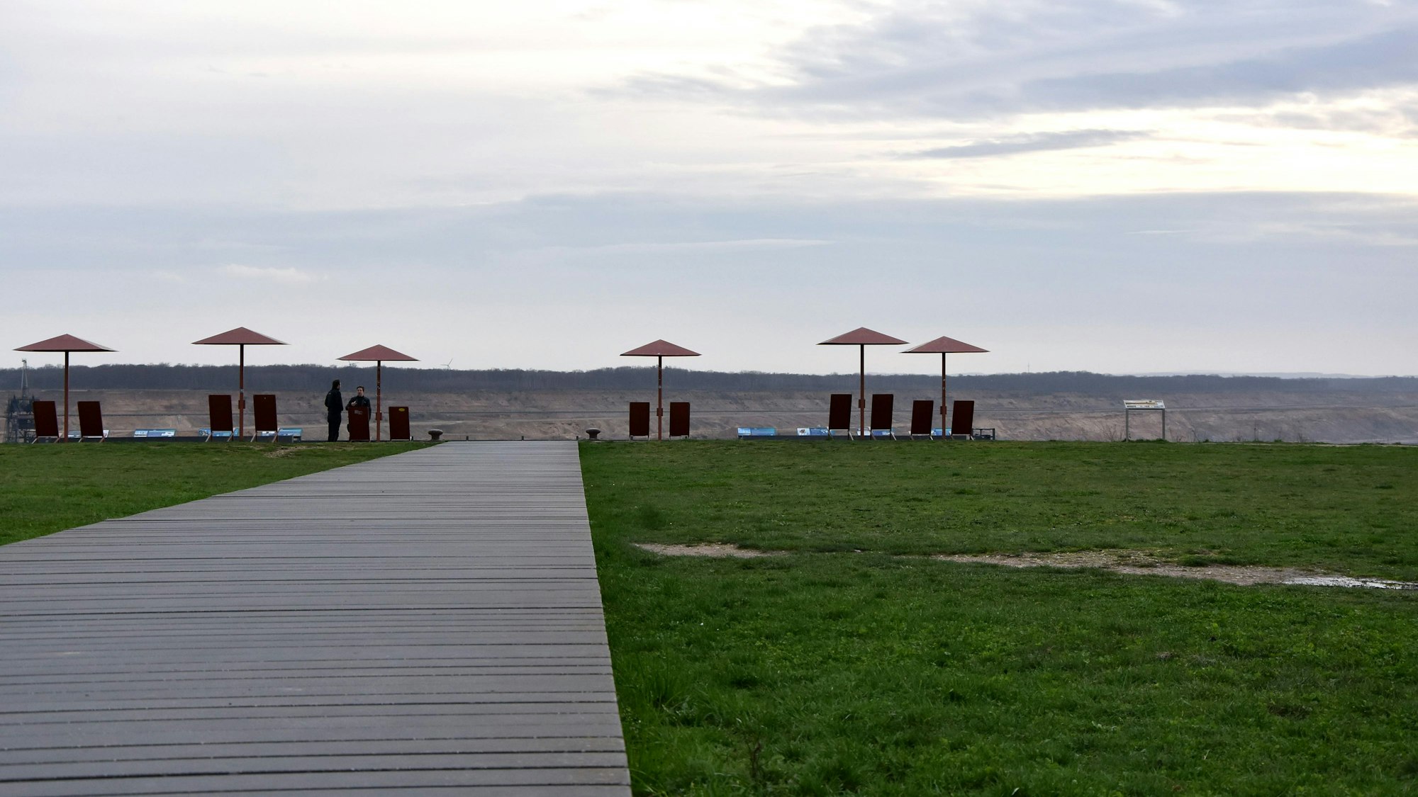 Ein Holzsteg führt zu einem Tagebaurand.