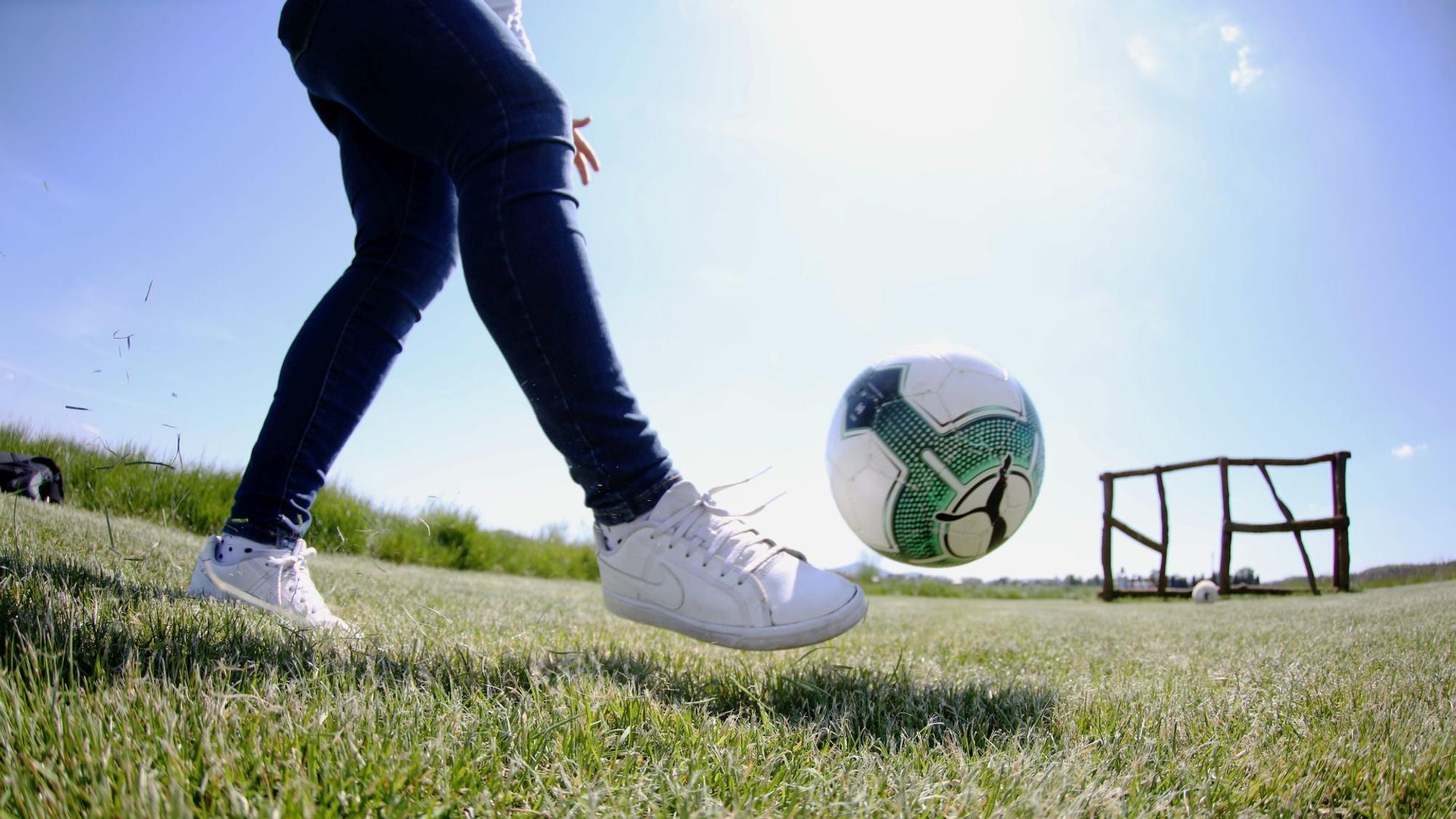 Eine Frau schießt einen Ball Richtung eines Ziels.
