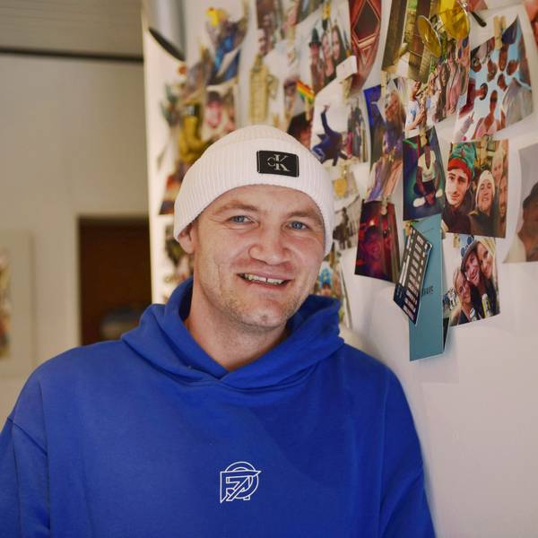 Jan Schepanek steht in seiner Wohnung vor einer Wand mit vielen Fotos, die ihn beim Feiern zeigen.