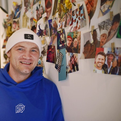 Jan Schepanek steht in seiner Wohnung vor einer Wand mit vielen Fotos, die ihn beim Feiern zeigen.