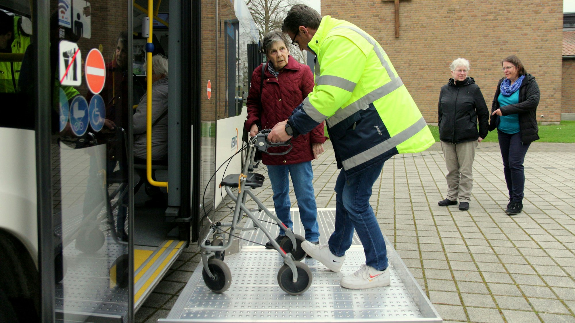 Ein Mitarbeiter der Rhein-Erft Verkehrsgesellschaft zeigt einer Senioren, wie sie ihren Rollator in den Bus heben kann.