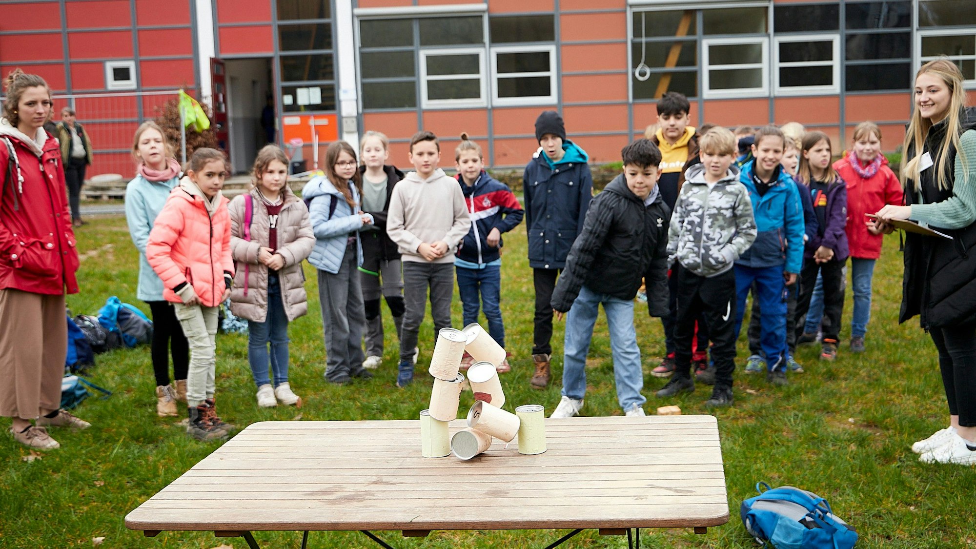 Ein Junge hat mit einem Ball einen Stapel Dosen umgeworfen. Andere Kinder schauen zu.
