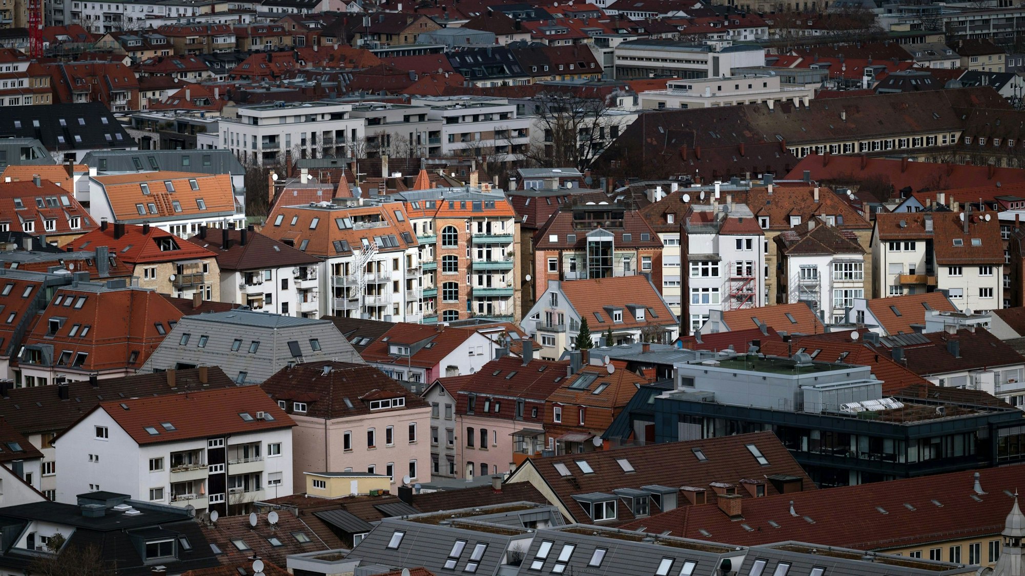 Vereinzelte Gebäude werden in der Stuttgarter Innenstadt durch ein Wolkenloch von der Sonne angestrahlt.