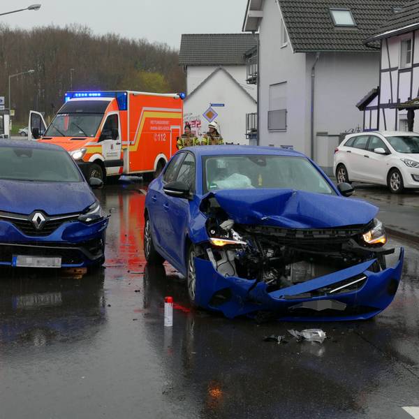 Zwei beschädigte blaue Autos stehen auf einer Straße.