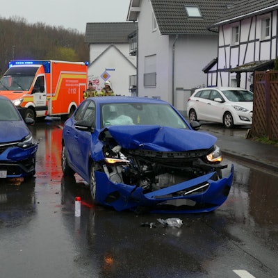 Zwei beschädigte blaue Autos stehen auf einer Straße.