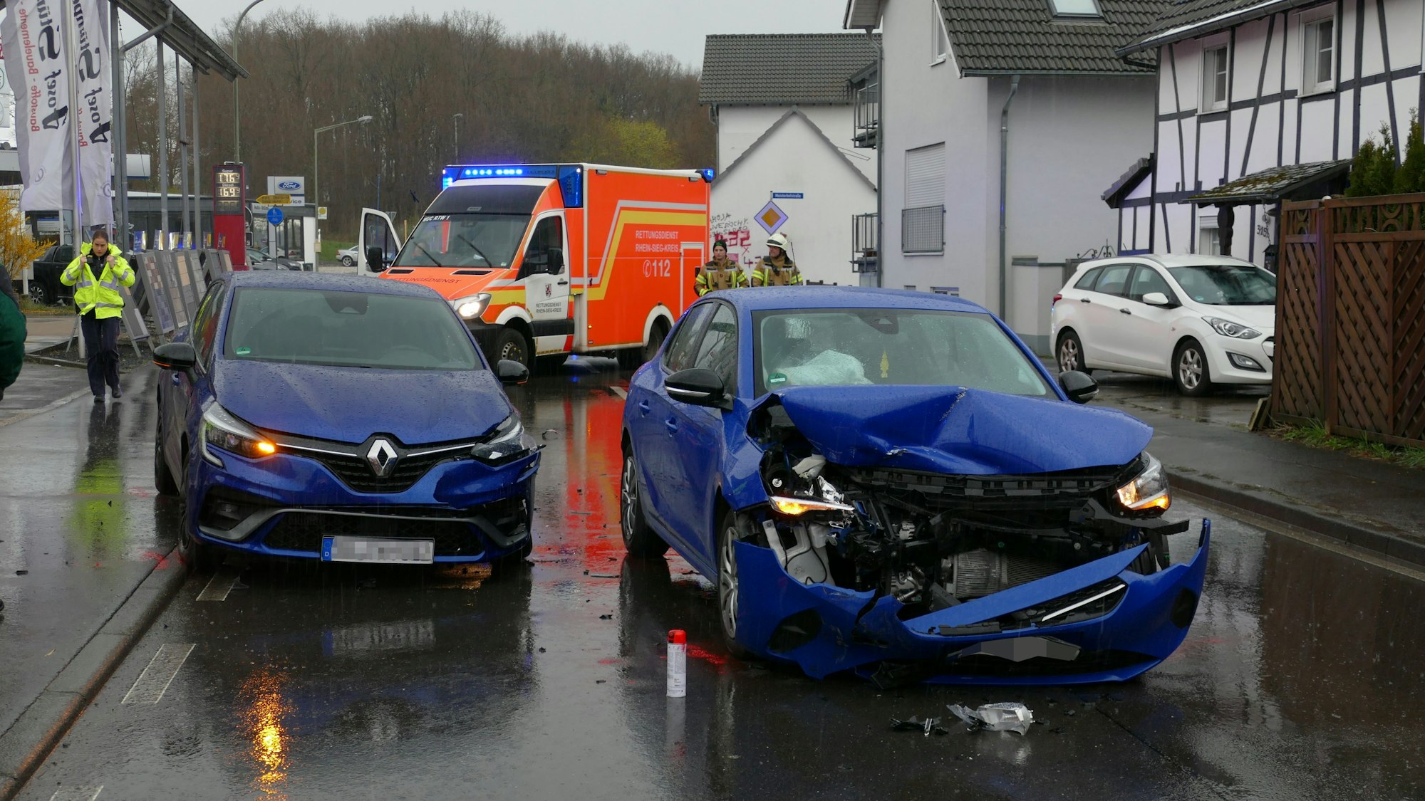 Zwei beschädigte blaue Autos stehen auf einer Straße.