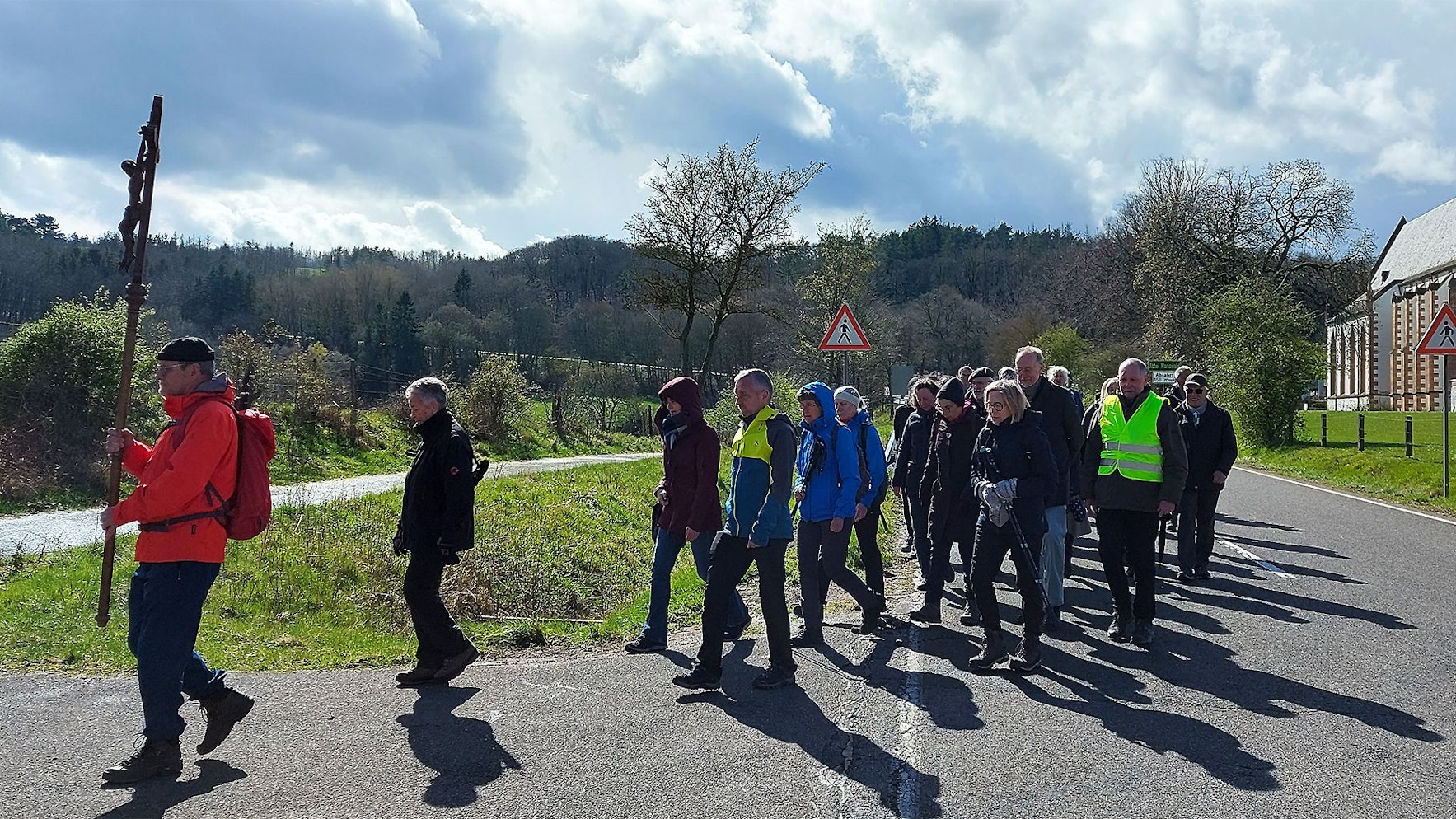 Der erste Pilger trägt ein Kreuz und die anderen folgen ihm.