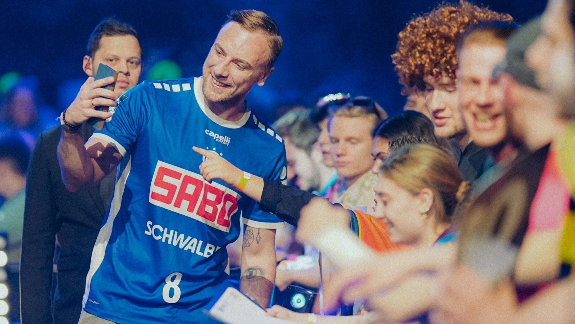VfL-Handballer Lukas Blohme macht bei einer Darts-Gala in Gummersbach Selfies mit den Fans.