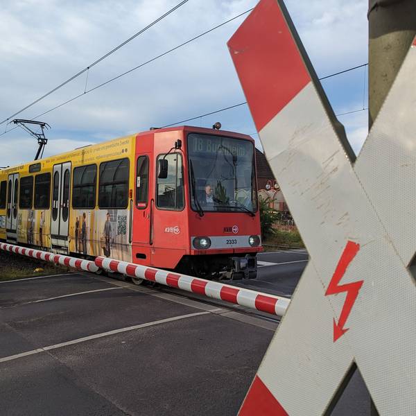 Auf dem Foto ist die Stadtbahnlinie 18 an einem Bahnübergang zu sehen.
