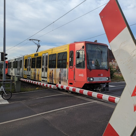Auf dem Foto ist die Stadtbahnlinie 18 an einem Bahnübergang zu sehen.