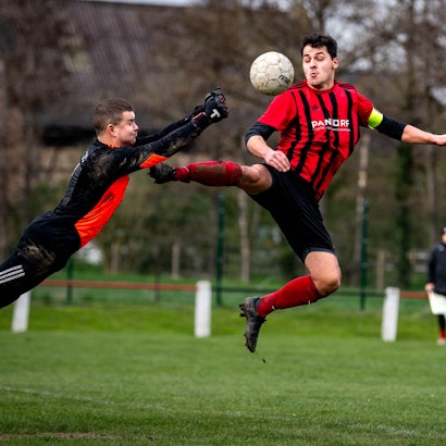 Das Bild zeigt die spektakuläre Rettungstat des Euskirchener Torwarts, der mit beiden Fäusten voran in Richtung seines Gegenspielers springt.