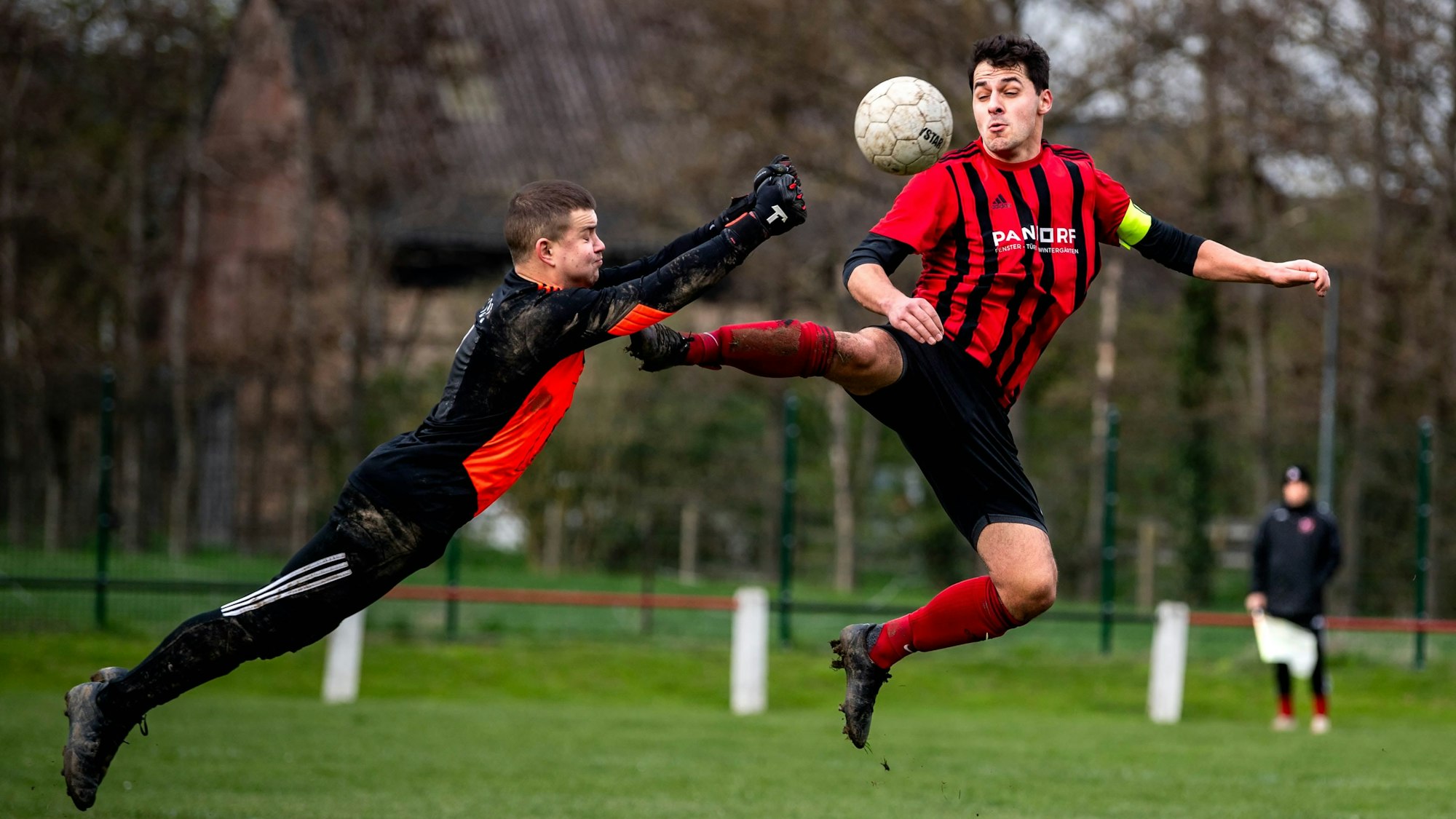 Das Bild zeigt die spektakuläre Rettungstat des Euskirchener Torwarts, der mit beiden Fäusten voran in Richtung seines Gegenspielers springt.