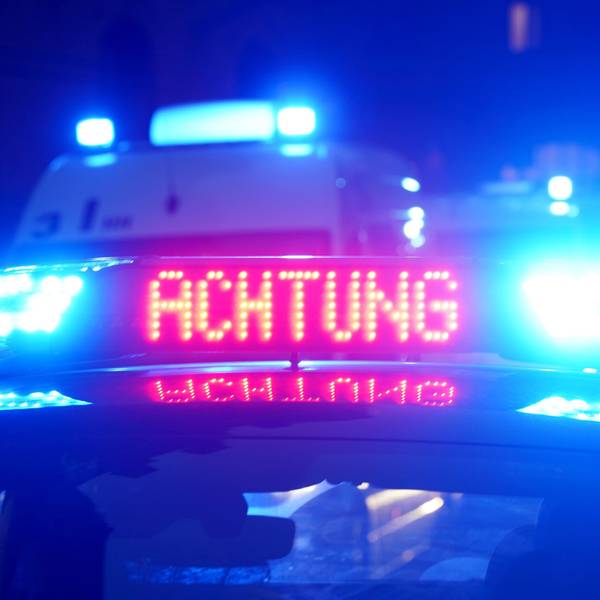 Das Bild zeigt einen Polizeiwagen in der Dunkelheit mit eingeschaltetem Blaulicht.