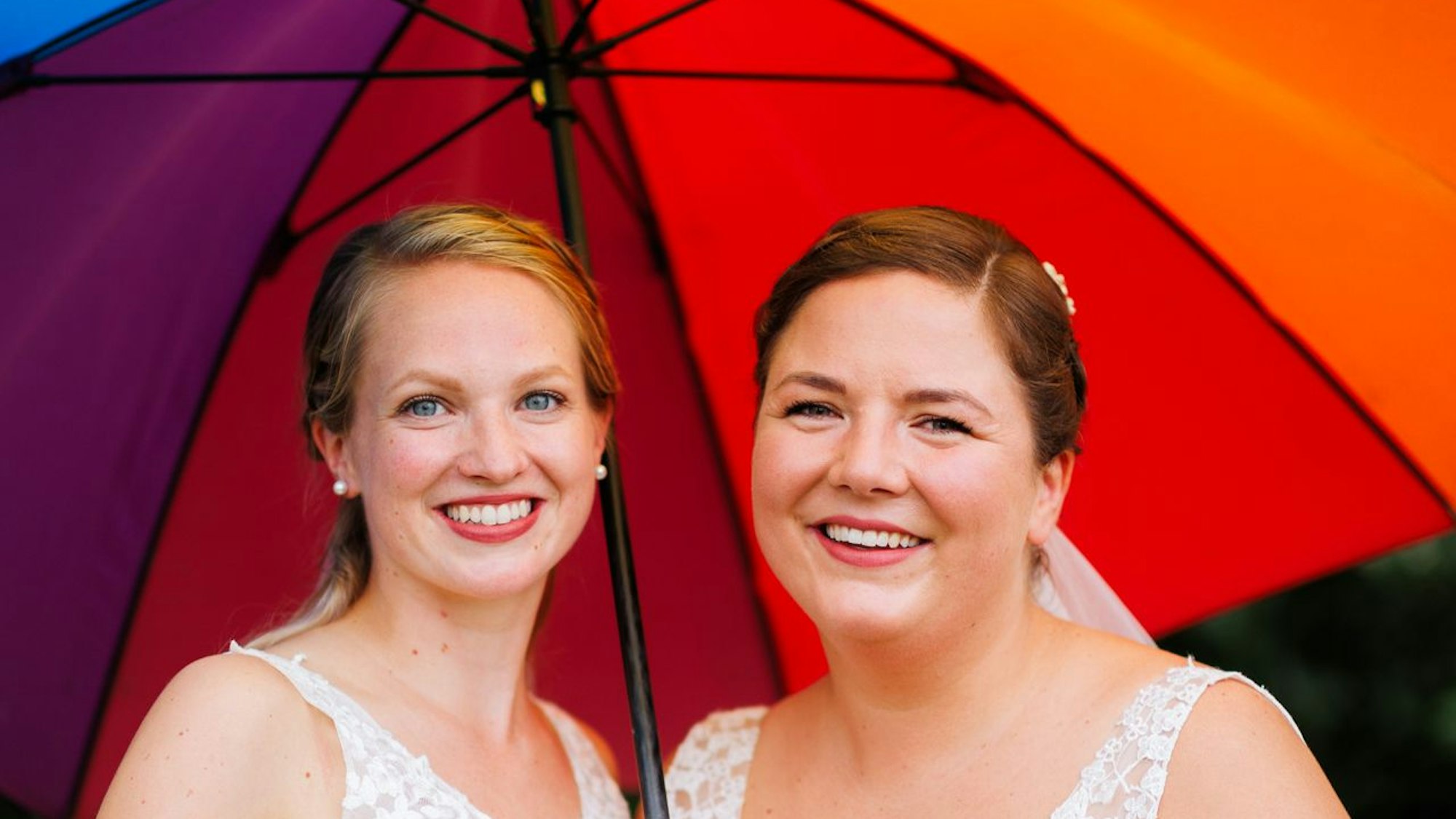 Laura und Christel Wendeler halten einen Regenbogen-Regenschirm.