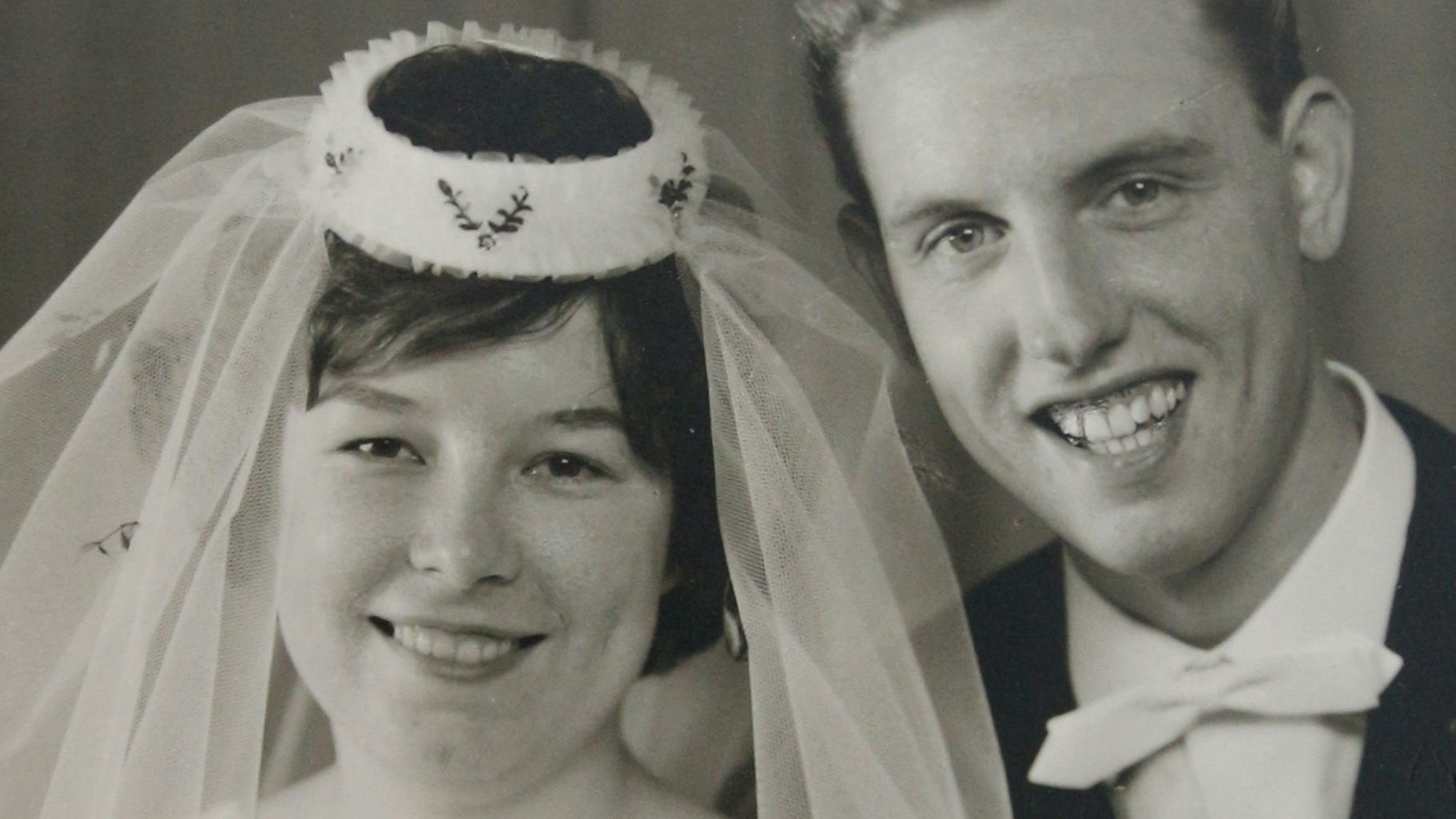 Das Brautpaar: Sie in Weiß mit Schleier, er im Anzug mit weißer Fliege.