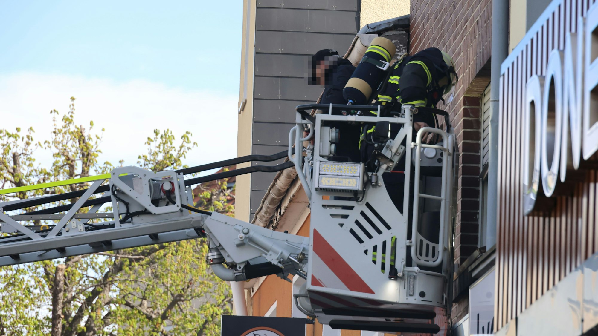 Der Hausbewohner und ein Feuerwehrmann werden im Korb der Drehleiter nach unten gefahren.