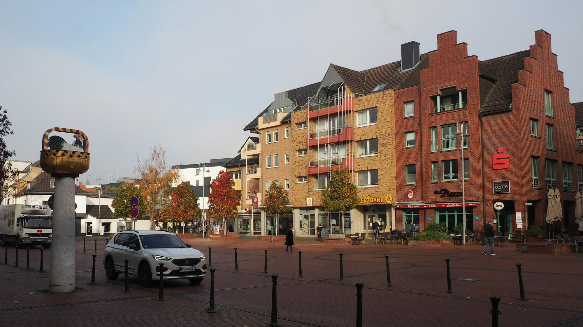 Der Marktplatz in Pulheim, links das Kunstwerk „Hahn im Korb“.