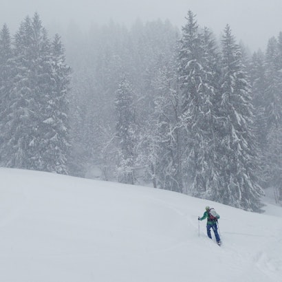Ein Skitourengeher steigt durch viel Neuschnee einen Berg hinauf. (Symbolbild)