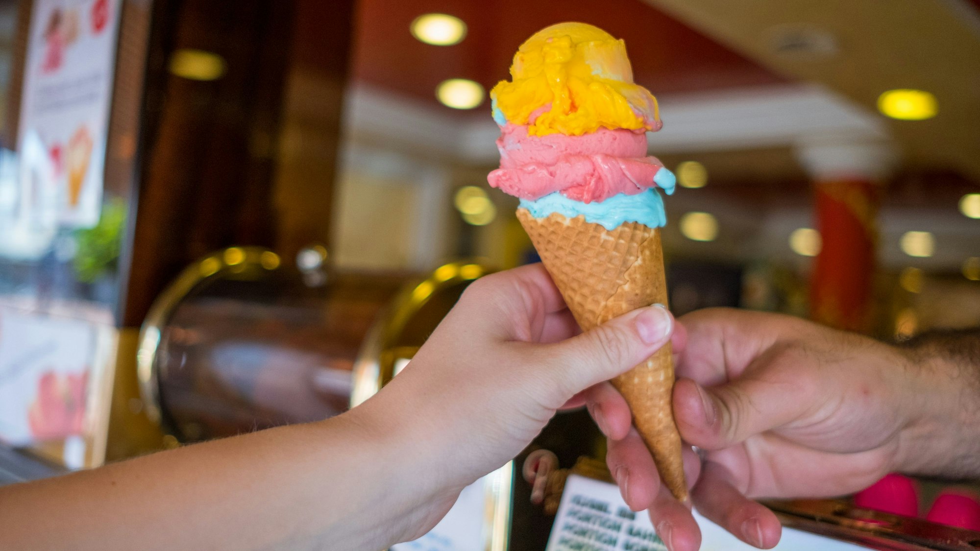 Eine Frau kauft drei Kugeln Eis in einer Waffel.