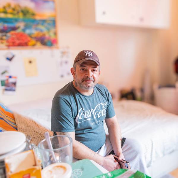 Ein Mann sitzt auf einem Bett.