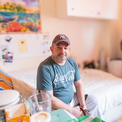 Ein Mann sitzt auf einem Bett.