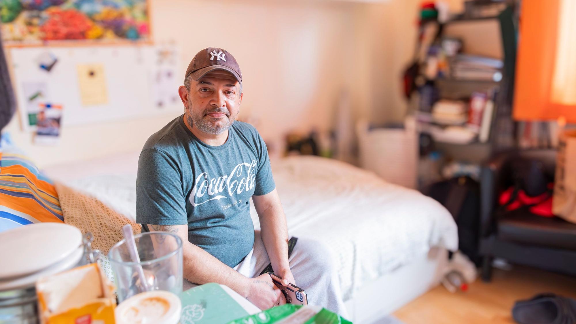 Ein Mann sitzt auf einem Bett.