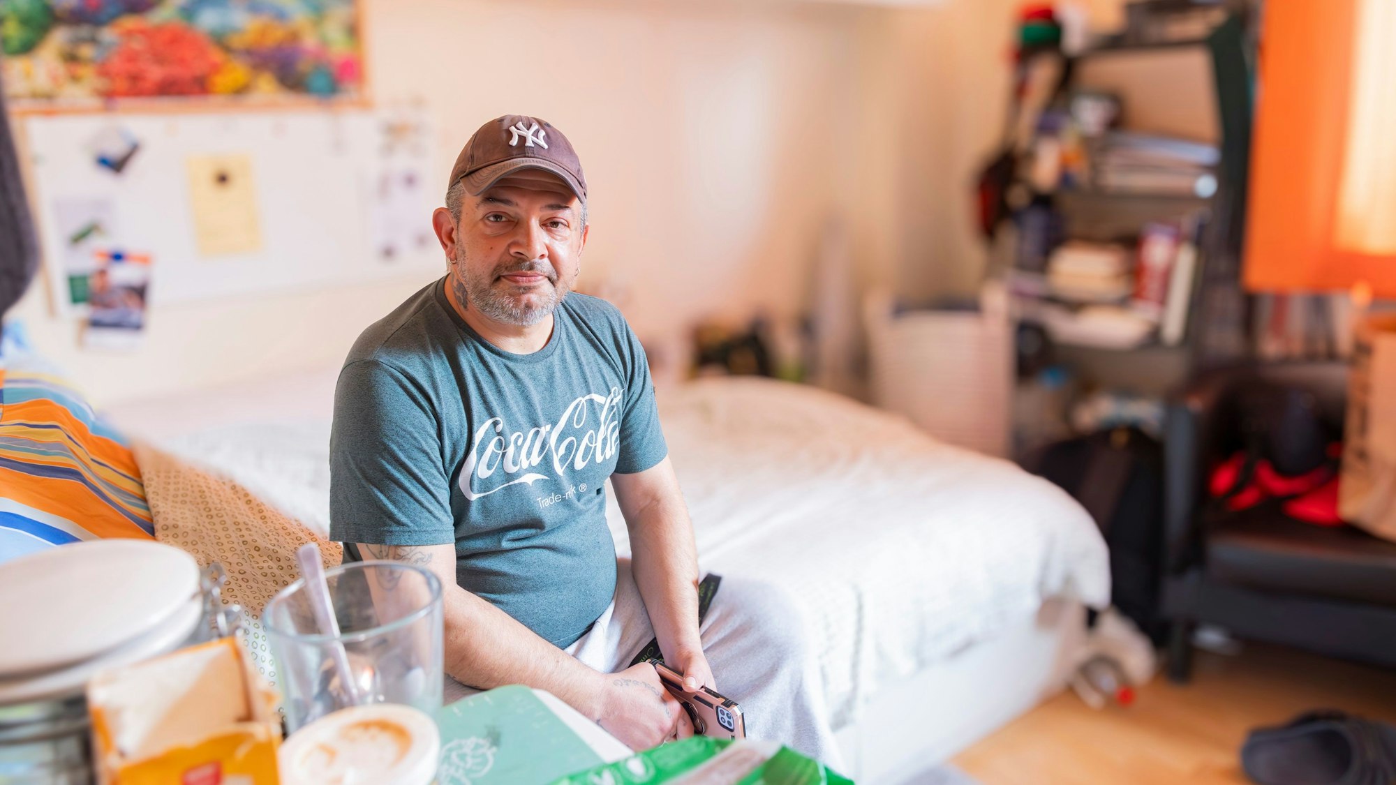 Ein Mann sitzt auf einem Bett.