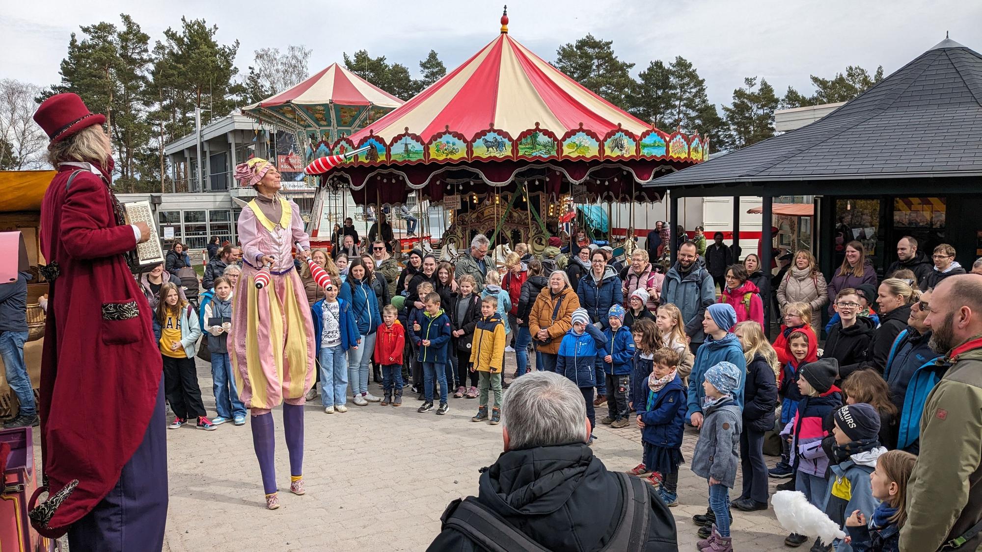 Beim Jahrmarkt anno dazumal im LVR-Freilichtmuseum Kommern verfolgen zahlreiche Besucher die Darbietungen von zwei Artisten auf Stelzen.