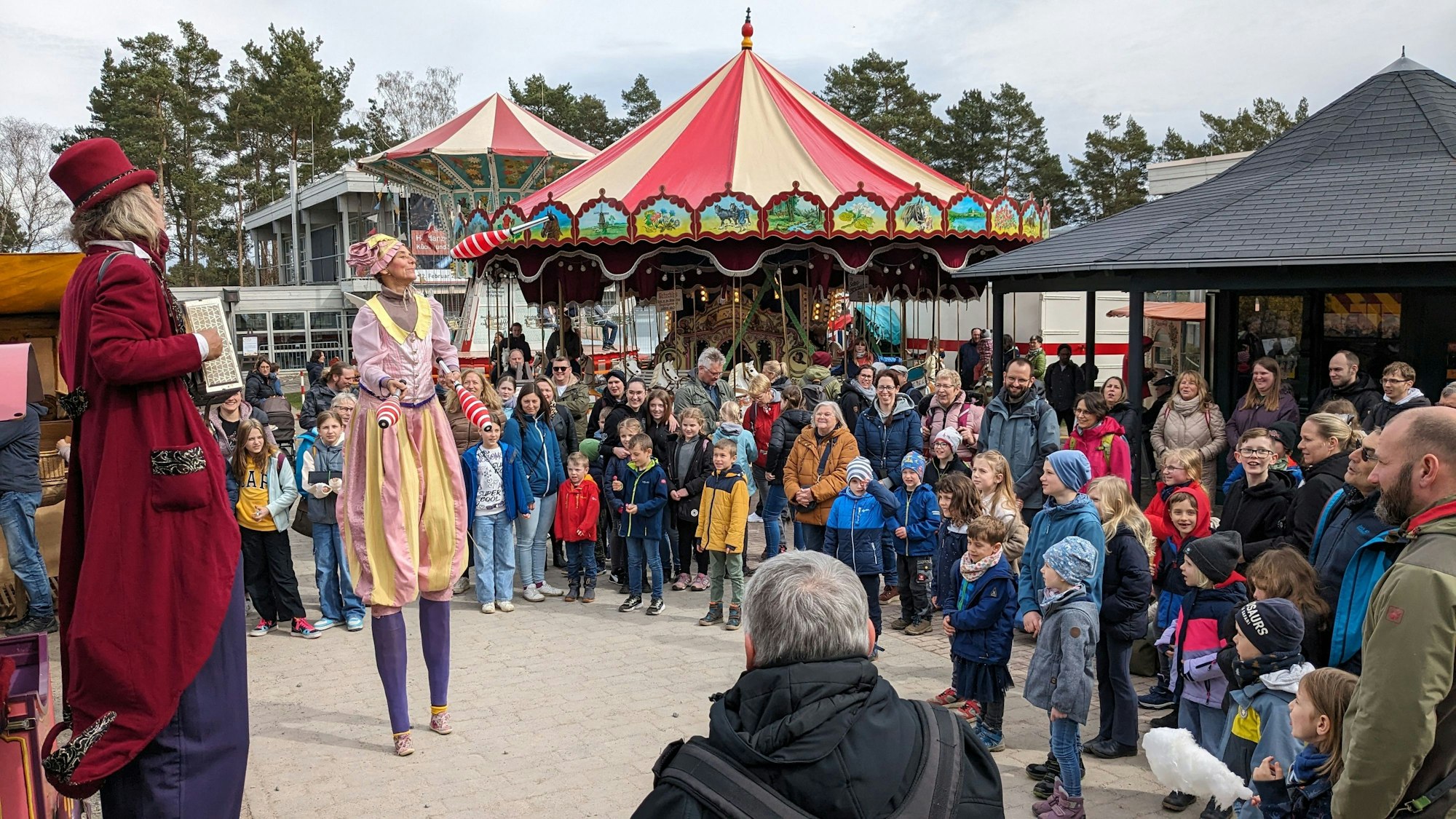 Zwei Stelzenläufer sind auf dem Jahrmarkt Anno dazumal im Kommerner Freilichtmuseum. Zahlreiche Zuschauer beobachten sie.