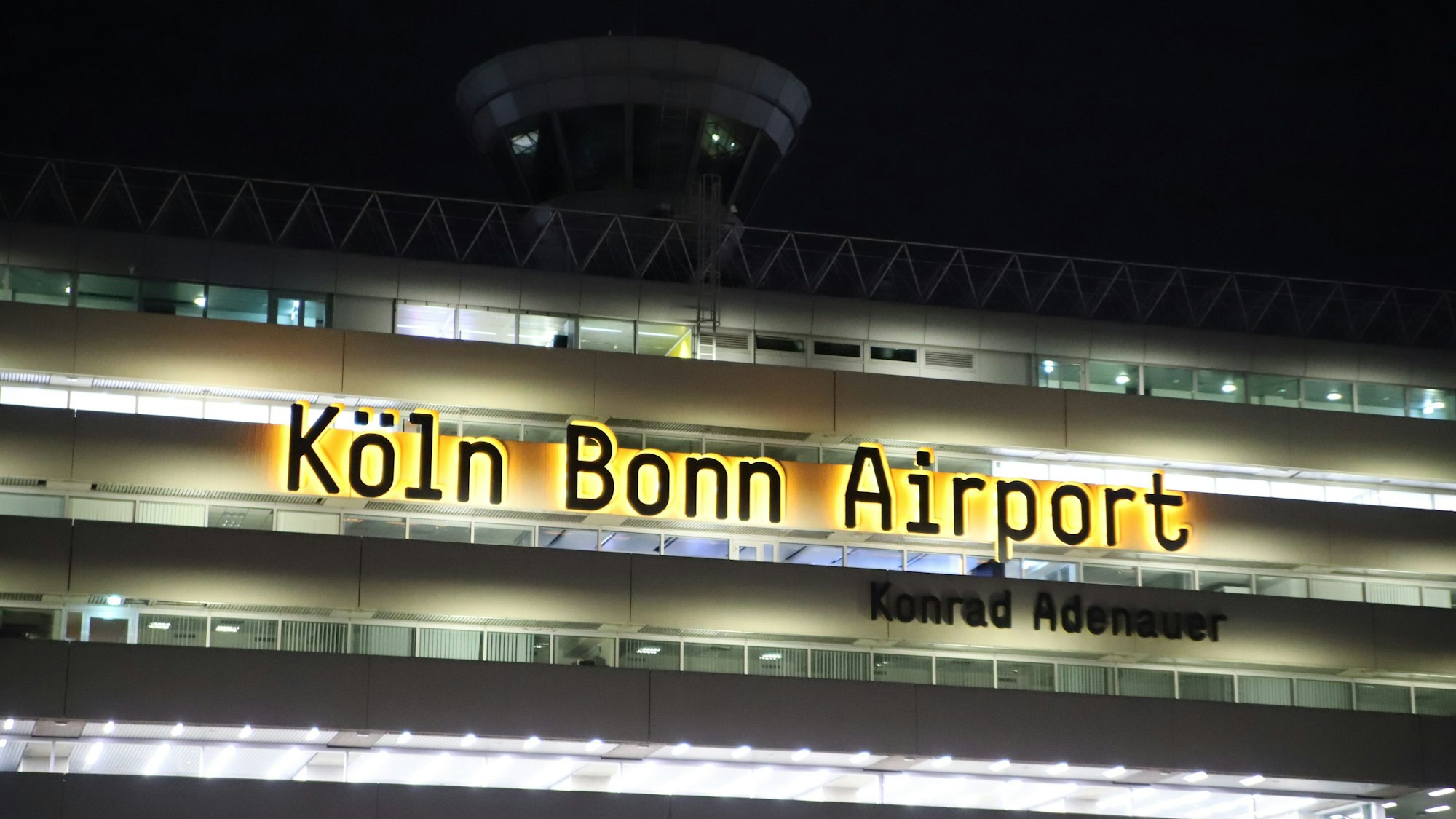 Das Logo Köln Bonn Airport am Terminalgebäude leuchtet noch am Flughafen Köln/Bonn.