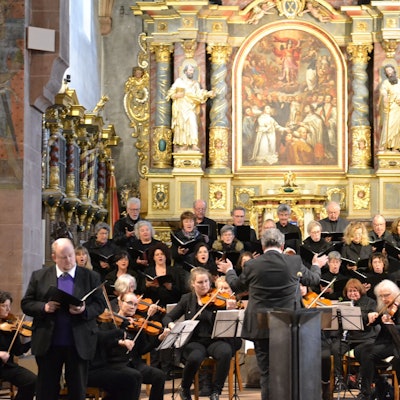 Orchester und Chor musizieren in der Basilika, im Hintergrund der Altar.