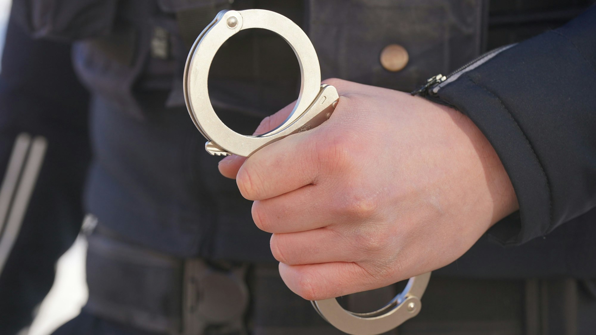 Ein Polizist hält Handschellen in der Hand.