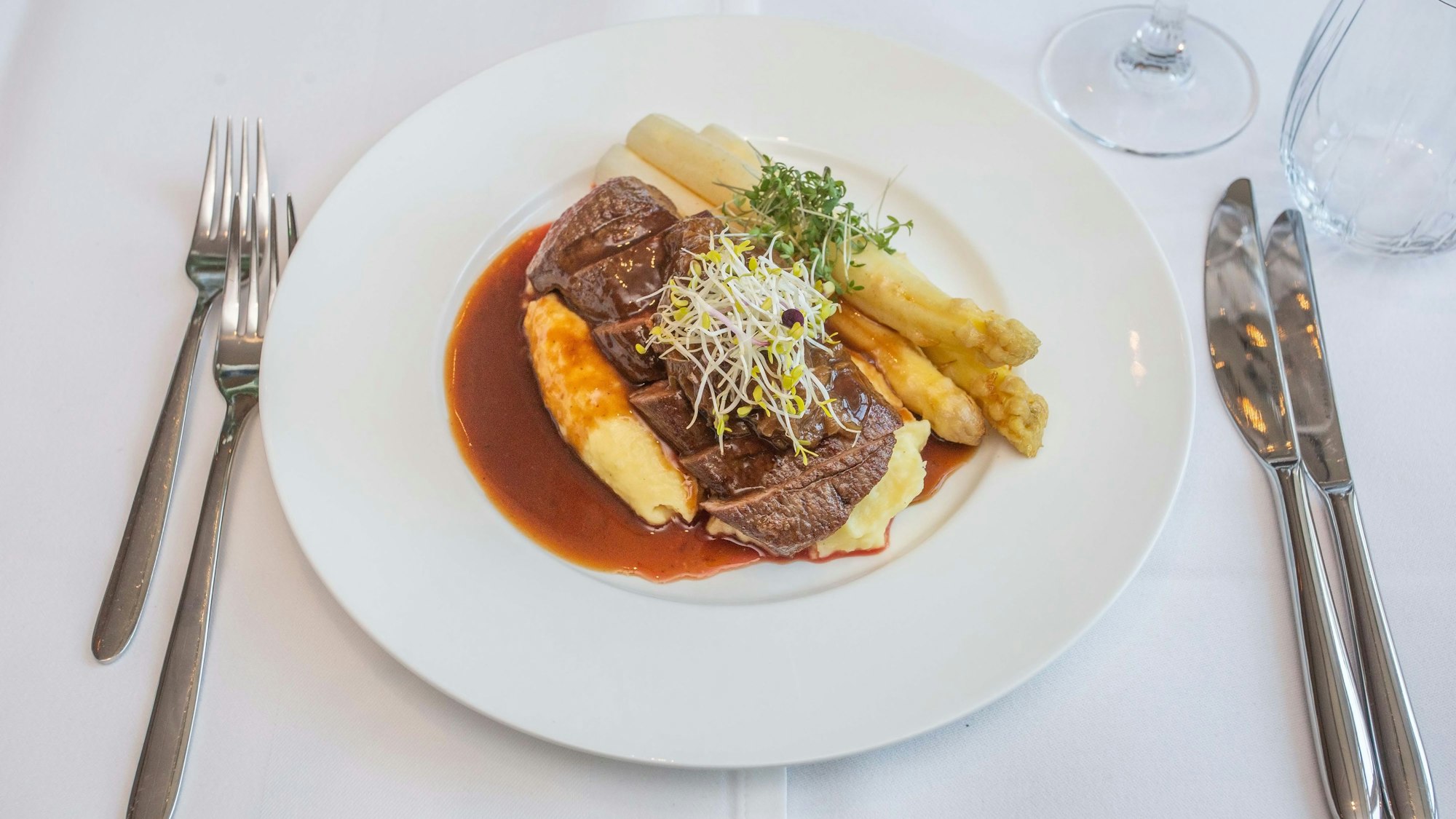 Der Hauptgang angerichtet: Lammlachs mit Kartoffelstampf, weißem Spargel, Zwiebelmarmelade und Lamm Jus.