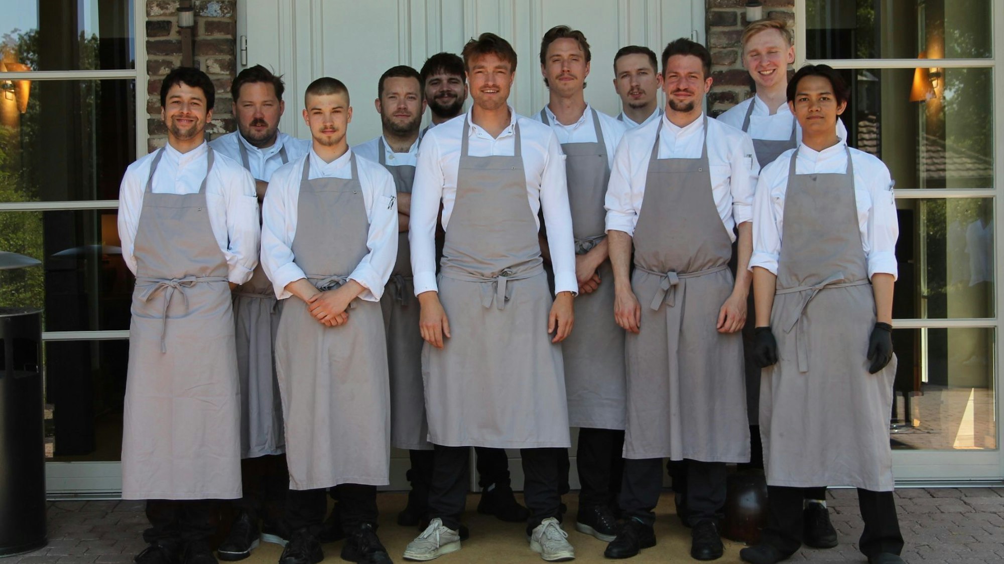 Zu sehen sind der Küchenchef und sein Team vor dem Eingang ins Restaurant.