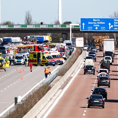 Einsatzfahrzeuge und Rettungshubschrauber stehen auf der A9 an der Unfallstelle.