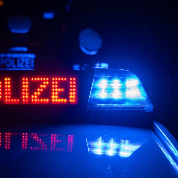 Zwei Polizisten stehen im Rahmen eines Fototermins vor einem Polizeifahrzeug (gestellte Szene).