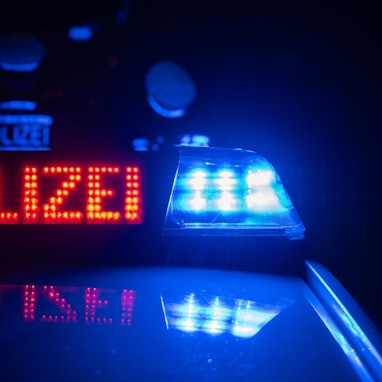 Zwei Polizisten stehen im Rahmen eines Fototermins vor einem Polizeifahrzeug (gestellte Szene).