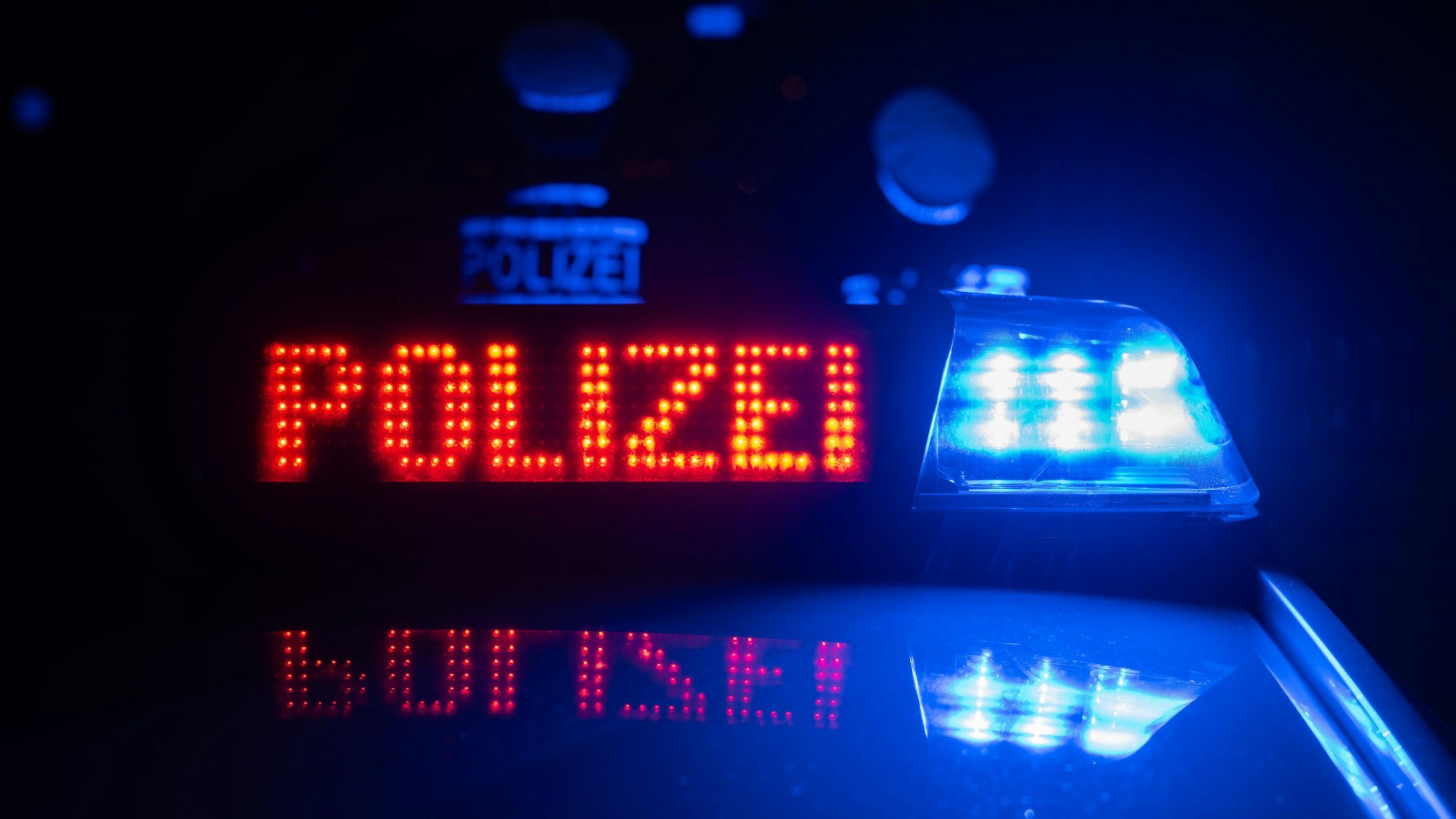 Zwei Polizisten stehen im Rahmen eines Fototermins vor einem Polizeifahrzeug (gestellte Szene).