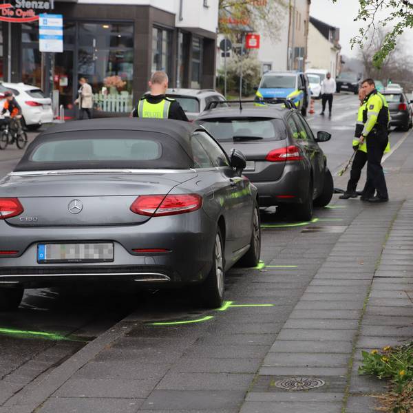 Autos stehen auf einem Bürgersteig. Polizisten haben Markierungen gezogen.