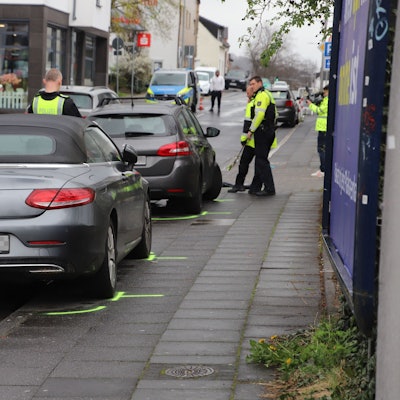 Autos stehen auf einem Bürgersteig. Polizisten haben Markierungen gezogen.