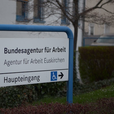 Ein Schild in einem blauen Rahmen weist den Weg zum Gebäude der Bundesagentur für Arbeit an der Thoméstraße in Euskirchen.