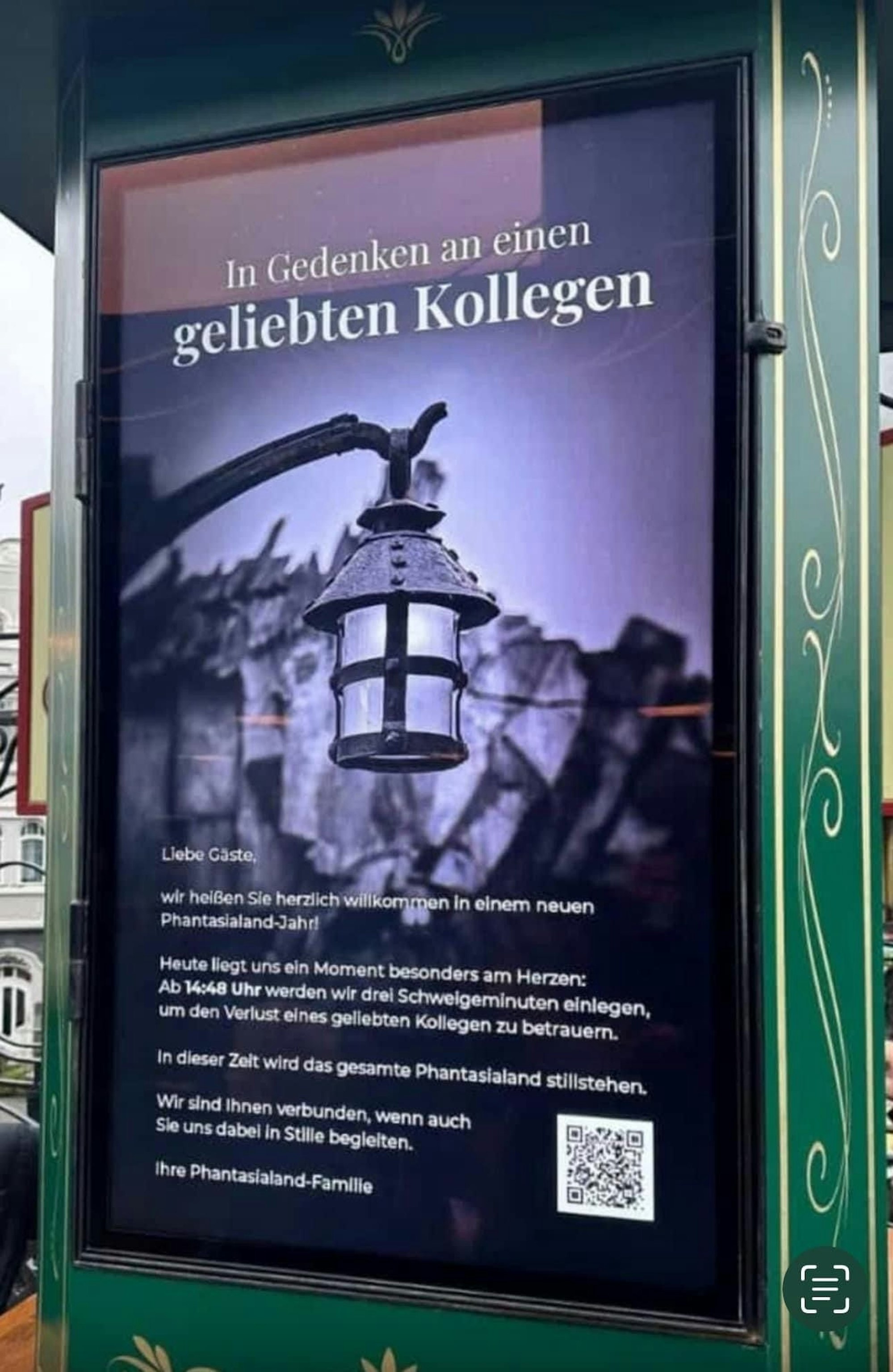 Auf dem Foto ist ein Plakat zu sehen, auf dem das Management des Phantasialands die Besucher bittet, sich an der Schweigeminute für den verstorbenen Mitarbeiter zu beteiligen.