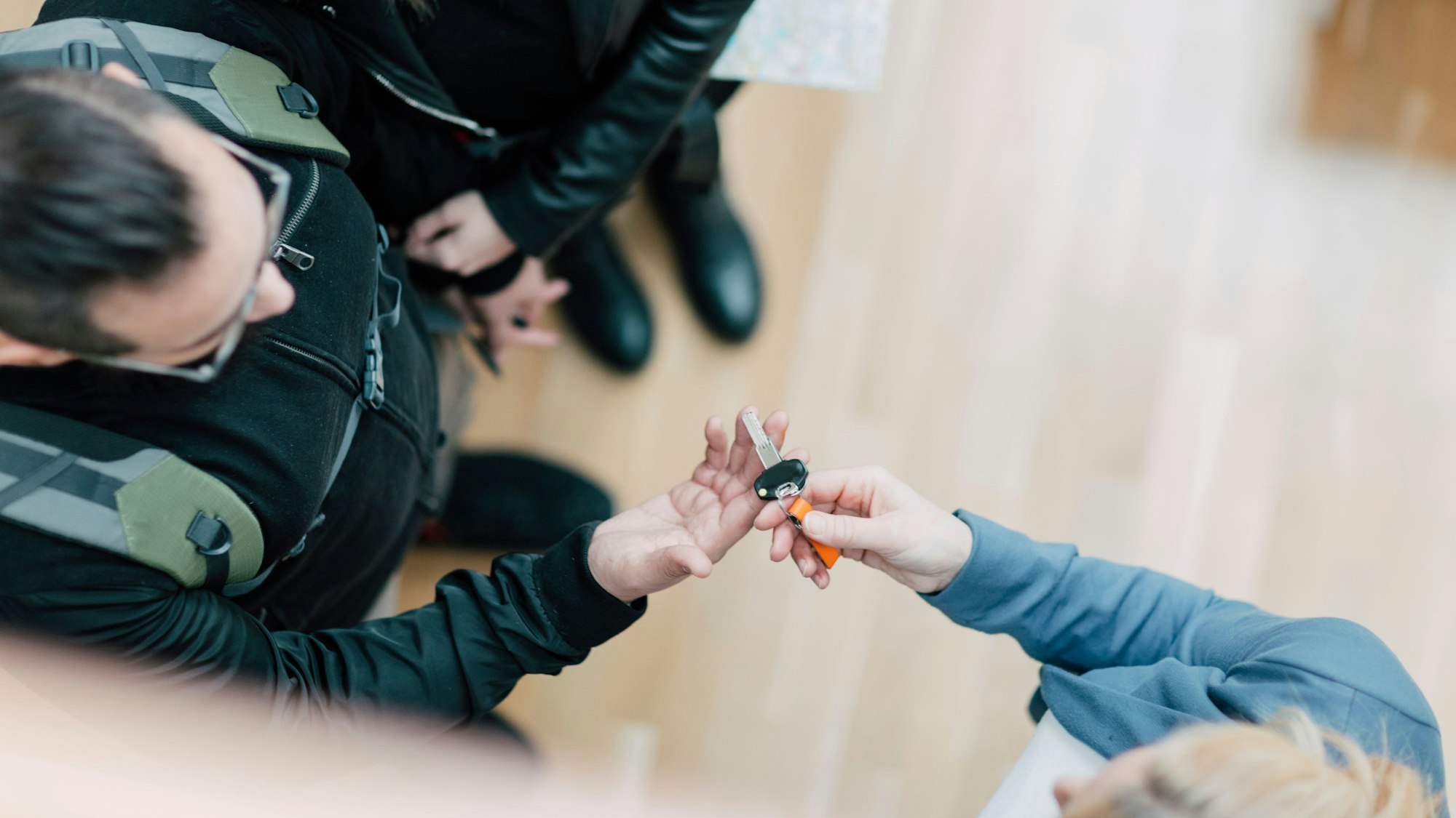 Eine Person übergibt zwei anderen Personen einen Schlüssel