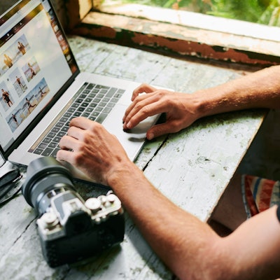 Mann bearbeitet Fotos am Laptop. Symbolbild