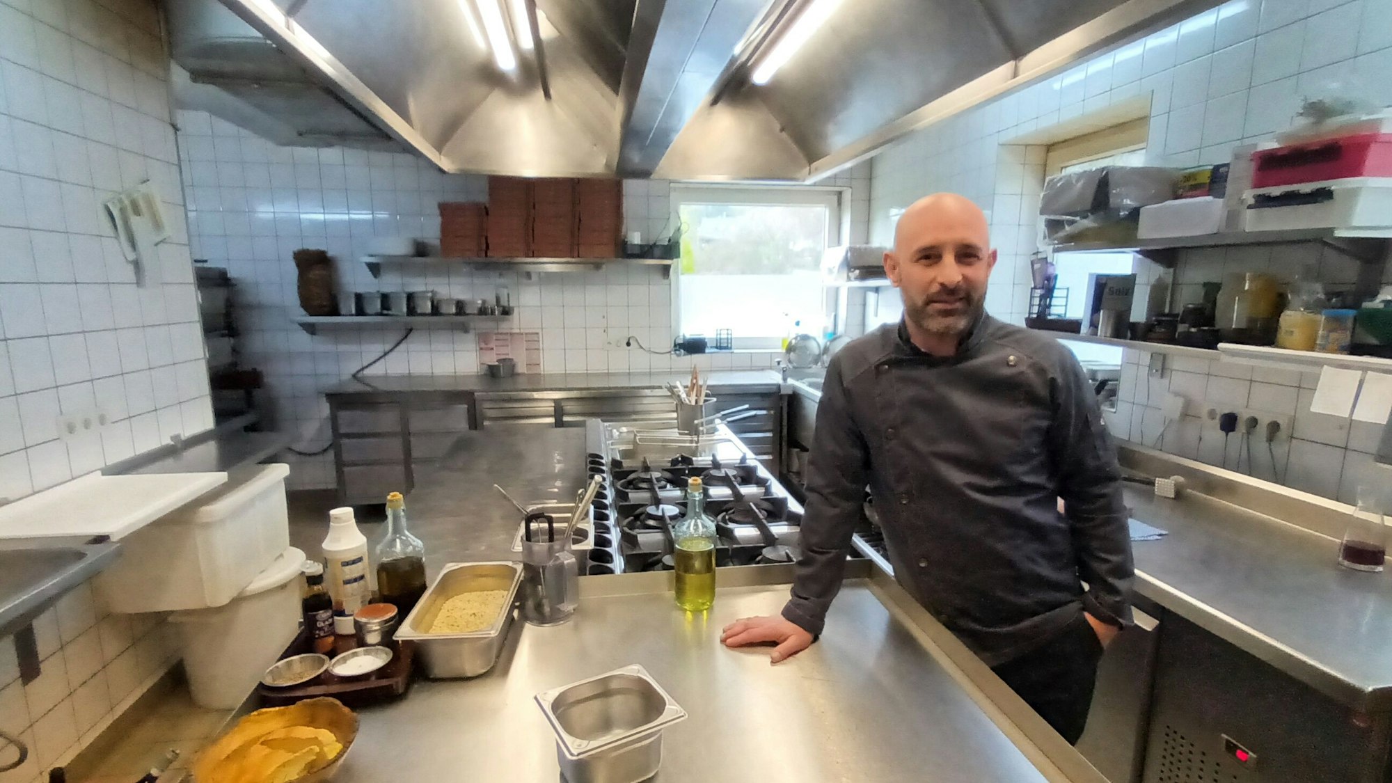 Mann in Kochjacke in einer Restaurantküche