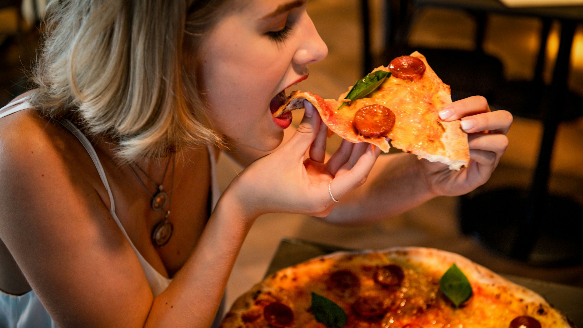 Zu sehen ist eine Frau, die Pizza isst.